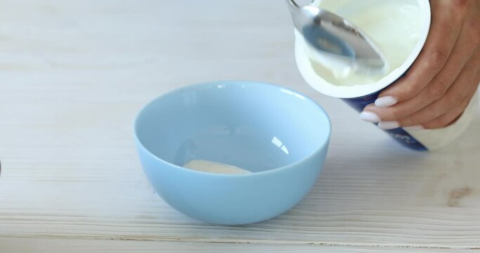 Yogurt or sour cream is placed in a bowl from the package. Breakfast preparation. Healthly food.
