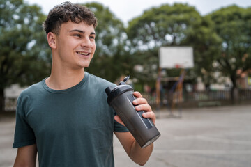 one young caucasian man teenager hold supplement shaker stand outdoor