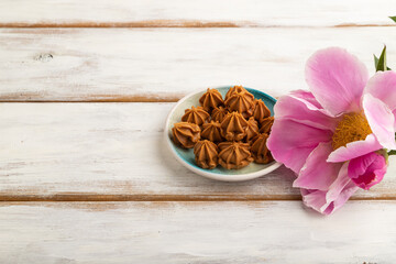 Homemade soft caramel fudge candies on white wooden, side view, copy space.