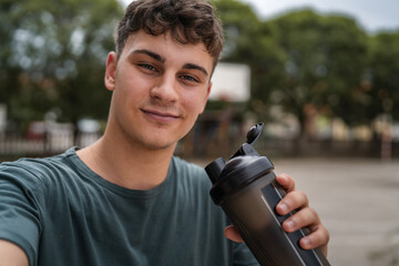 one young caucasian man teenager hold supplement shaker stand outdoor