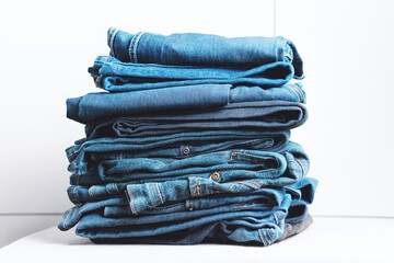 Denim jeans stacked on a white background. Trend clothes, shopping.