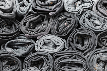 Lots of folded black and gray jeans. Denim background. Fashion denim clothing, shopping, fashion, consumption. - obrazy, fototapety, plakaty