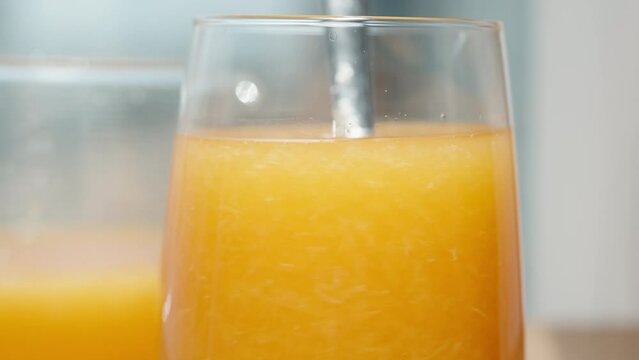 Close-up of me stirring the pulp in the orange juice, in slow motion.