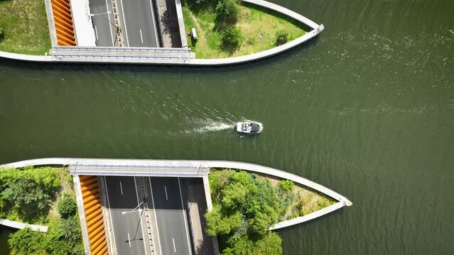 Aerial  footage of a motorboot passing the aqueduct Veluwemeer above the highway. View of water bridge Aquaduct Veluwemeer allowing vehicular and waterborne traffic to pass over or under one another. 