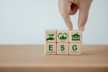 ESG text , environmental, social and governance. Sustainable corporation development. Hand holds wooden cubes with abbreviation ESG standing with other ESG icons , copy space