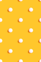 Pattern made of white ping pong ball on a bright yellow background. Creative layout.