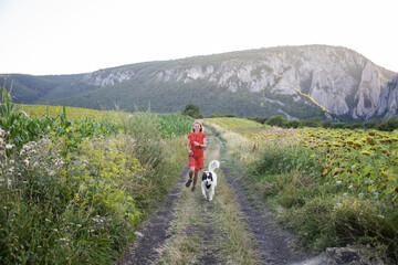 woman in red dress with white dog in nature