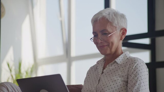 Mature Woman Working on Laptop on Sofa Close Up