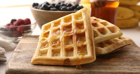 A stack of Belgian waffles drizzled with honey. Baking on the table with berries. Sweet food.