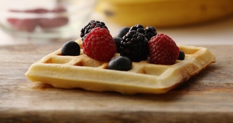 Blueberries and raspberries on the Belgian waffle. Breakfast preparation. Sweet food.