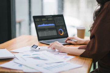 The data analyst woman working on a business analytics dashboard, utilizing charts and metrics to...