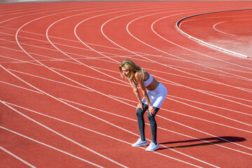 Break, tired woman at stadium for a workout, training or breathing after cardio. Sports, race and...