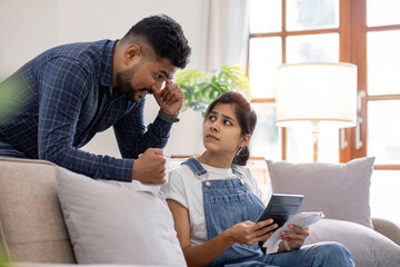 Young couple stressing about bills and invoices in living room Increased expenses cause stress.