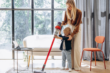 Mother with her son vacuuming carpet at home
