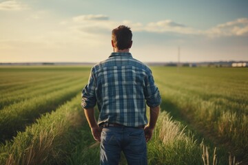 Naklejka na ściany i meble Farmer is wearing a plaid shirt in a wheat field, back view. AI generated