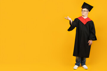 Smiling young man with down syndrome wearing glasses in graduation suit, place for text