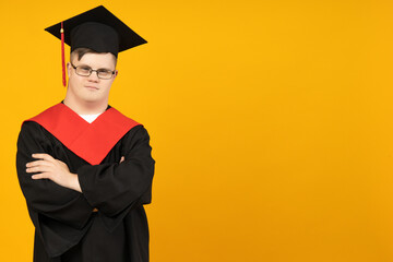 Smiling young man with down syndrome wearing glasses in graduation suit, place for text