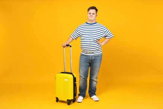 Smiling young man with down syndrome in glasses with suitcase