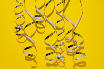 Silver swirling ribbons on yellow background, close up