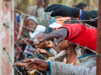 social unrest on the african continent, crowd of people hands seen through barbed wire fence