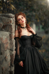Portrait of magnificent Fashion gothic girl  .Fantasy art work.Amazing red haired model in black dress looking at camera and posing.Fairytale about young princess 