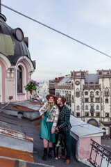 Beautiful couple in love with black dog on the roof at sunset in summer