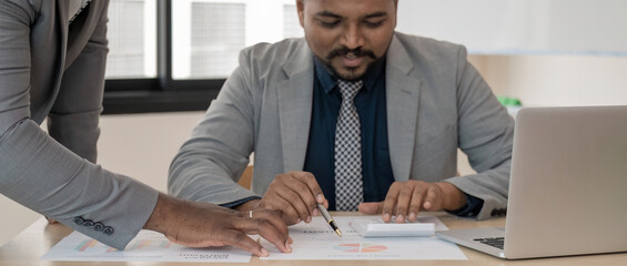 Businessman indian discuss analyze on financial to male African American colleague intern using laptop sitting in office