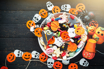 Fototapeta na wymiar decorated holiday table Halloween Jack o Lantern candy bowl with candy and halloween cookies Trick or Treat dark background
