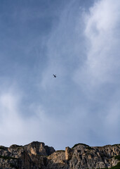 Fototapeta na wymiar A helicopter flies against the blue sky. Dolomites, Italy, Alps