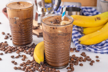 Blended banana coffee. Cold latte coffee and banana non-dairy, vegan diet drink with frozen bananas and espresso, on white kitchen table copy space