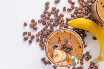 Blended banana coffee. Cold latte coffee and banana non-dairy, vegan diet drink with frozen bananas and espresso, on white kitchen table copy space