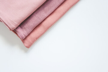 Stack of pink baby clothes on white background