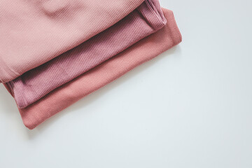 Stack of pink baby clothes on white background