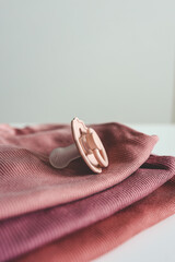 Stack of pink baby clothes and baby pacifier on white background