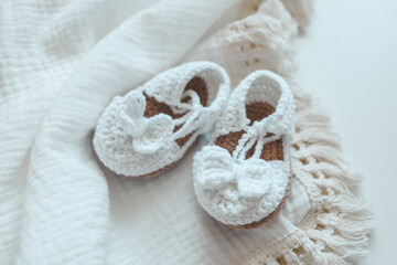 Baby muslin blanket and slippers top view on white background