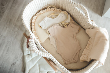 Two neutral bodysuits in a baby cradle, baby clothes
