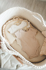 Two neutral bodysuits in a baby cradle, baby clothes