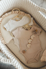 Obraz na płótnie Canvas Two neutral bodysuits in a baby cradle, baby clothes