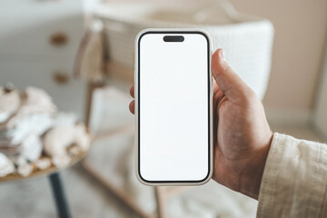 Pregnant woman showing blank smartphone screen while resting on couch at home. Expectant mom holding mobile phone with copy space for pregnancy track app, touching big belly