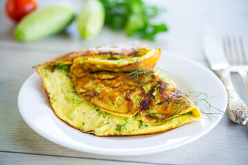 Fried omelet with zucchini, on a wooden table.