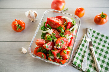 Spicy snack tomatoes with garlic, herbs, seasonings and onions in a glass bowl .