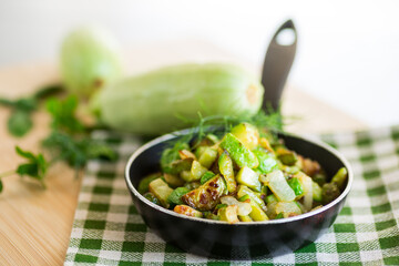 Sliced zucchini fried with onions and herbs in a frying pan