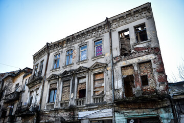 Fototapeta na wymiar Big cracks on the facade of an old building in Bucharest