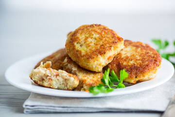 Cooked fried fish cutlets in a plate with herbs.
