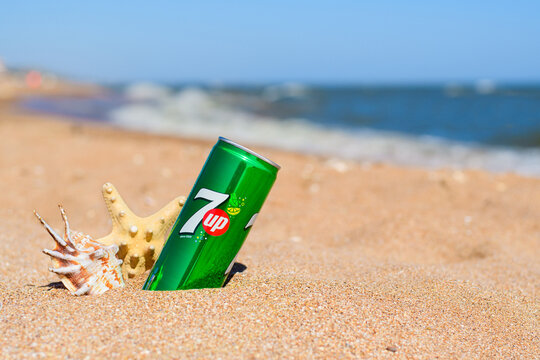 Anapa, Russia - 6 July 2023: Can of cold 7up and seashells on the sandy beach.