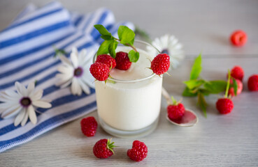 Sweet cooked homemade yogurt with fresh raspberries in a glass.