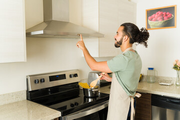 Happy man using his electric stove hood and cooking