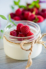 Sweet cooked homemade yogurt with fresh raspberries in a glass jar.