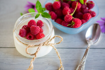 Sweet cooked homemade yogurt with fresh raspberries in a glass jar.