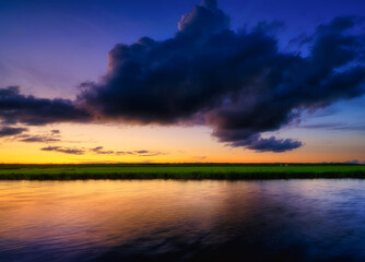 Seascape during sunset. Sunshine. A huge cloud in the sky after a storm. Natural landscape. Wallpaper and background.